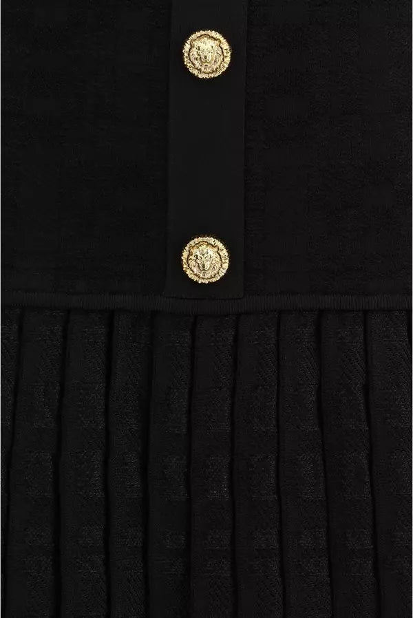 Black pleated dress with gold buttons on a black background