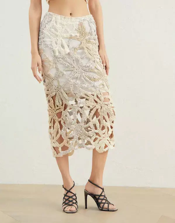 Person wearing a detailed lace skirt on a plain background