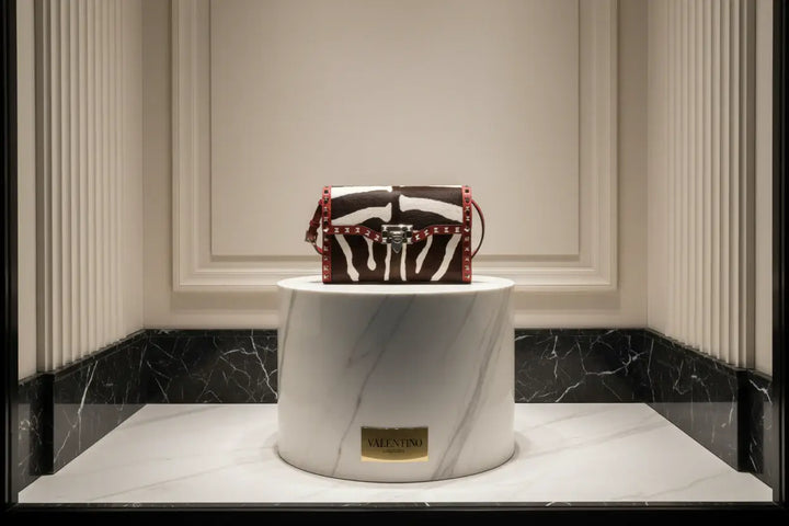 Zebra print handbag with red accents and silver studs on a white background