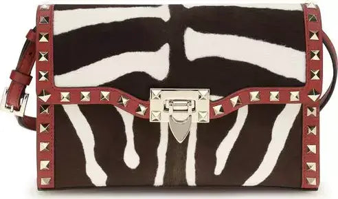 Zebra print handbag with red accents and silver studs on a white background