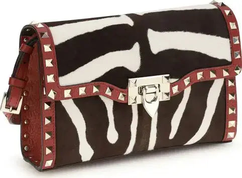 Zebra print handbag with red accents and silver studs on a white background