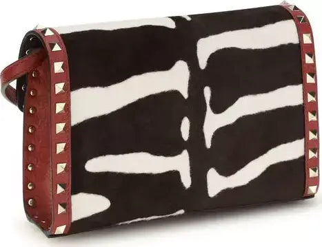 Zebra print handbag with red accents and studs on a white background