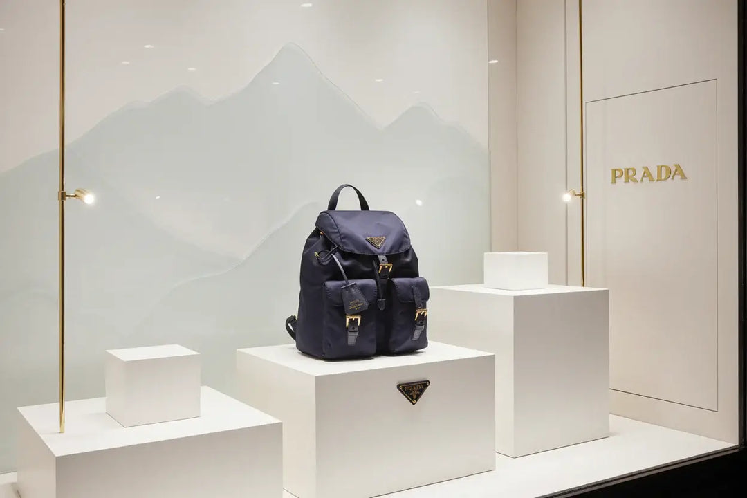 Navy blue Prada backpack with gold buckles on a white background