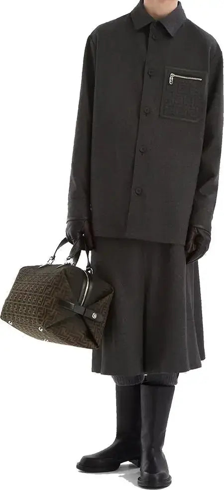 Person wearing a black outfit with a textured bag on a white background