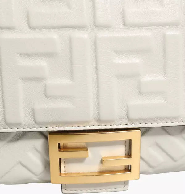 Close-up of a white quilted handbag with a gold logo clasp.