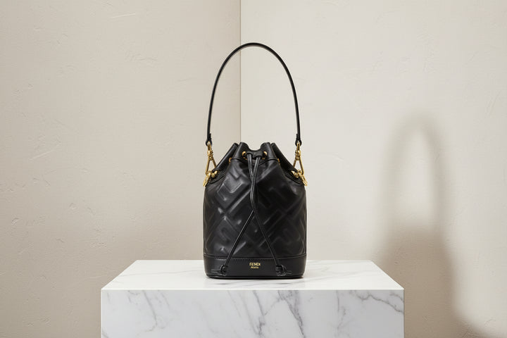 Black quilted handbag with gold accents on a white background