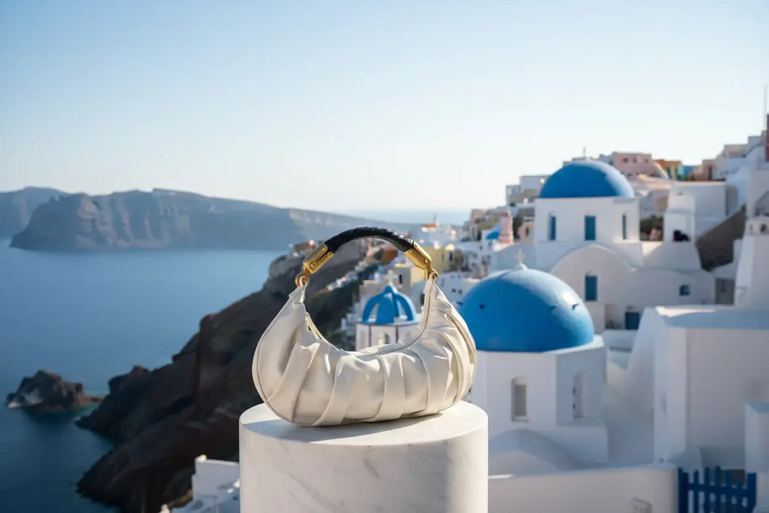 White handbag with gold and black handle on a white background