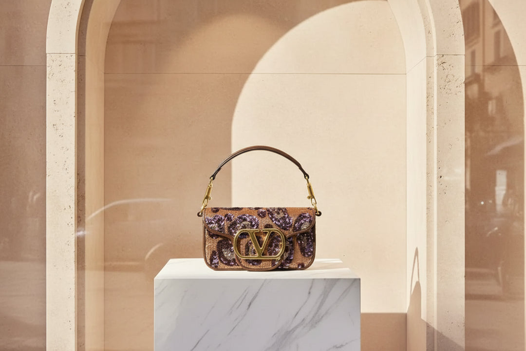 Designer handbag with sequin detailing and gold logo on a white background