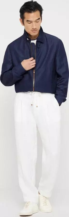Man wearing a navy jacket and white pants on a white background