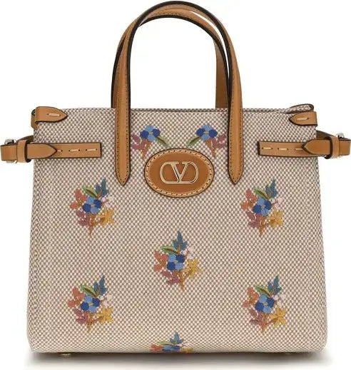 Handbag with floral pattern and brown handles on a white background