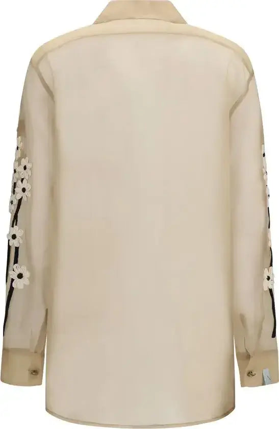 Beige shirt with floral patterns on sleeves against a white background