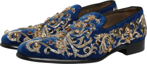 Blue velvet loafers with gold embroidery and embellishments on a white background