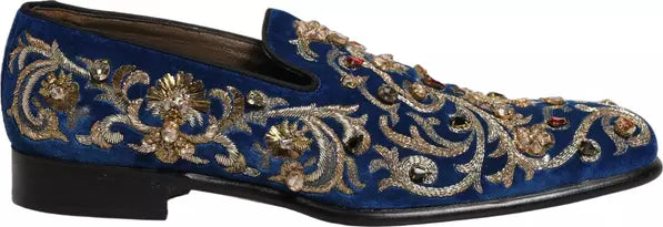 Blue loafers with gold embroidery and embellishments on a white background