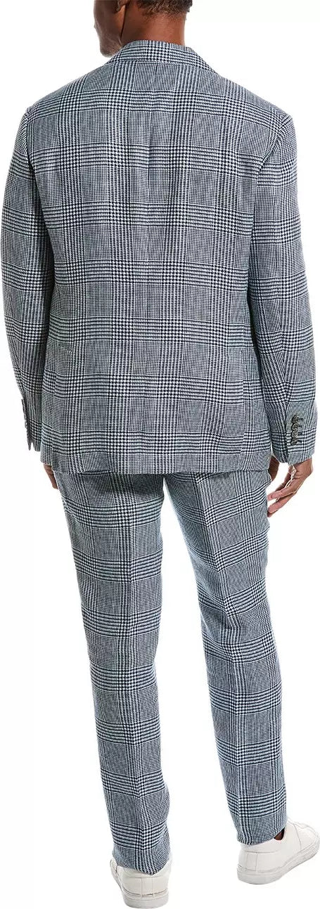 Man wearing a blue checkered suit with white sneakers on a plain background