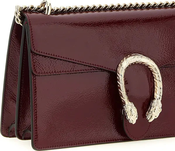 Burgundy handbag with gold snake clasp on a white background