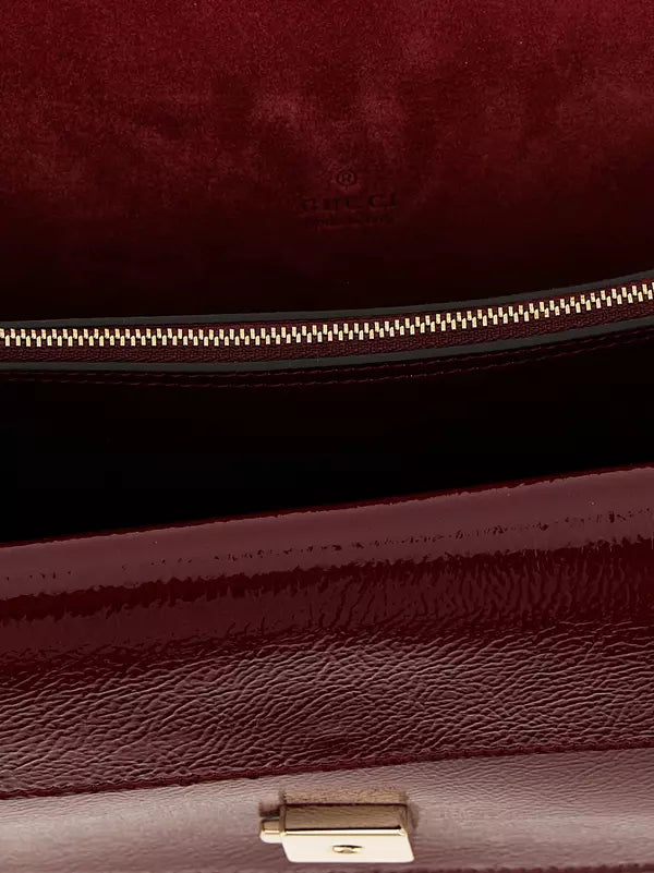 Close-up of a maroon handbag with a gold zipper and visible brand logo.