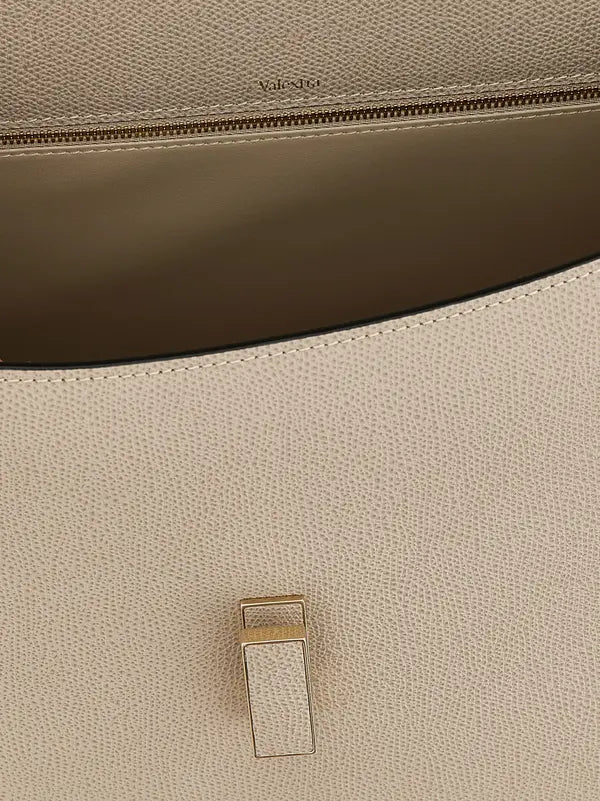 Close-up of a beige leather bag with a gold buckle detail, featuring the brand 'Valentino'.