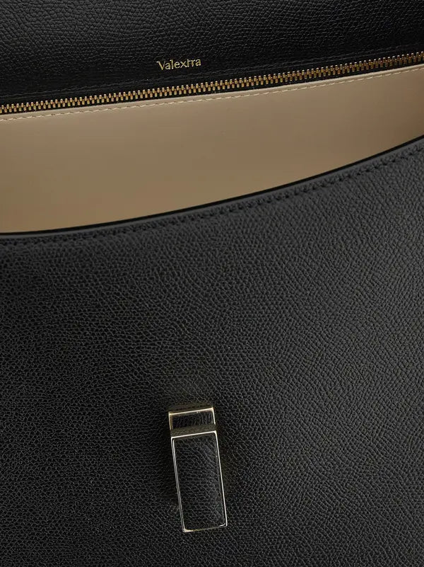 Close-up of a black leather bag with a gold zipper and Valextra branding.