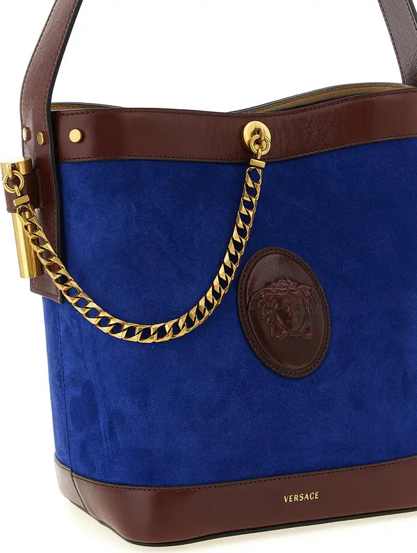 Blue handbag with brown accents and gold chain handle, featuring Versace logo.