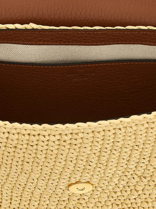 Close-up of a brown leather handbag with beige woven top and visible brand logo.