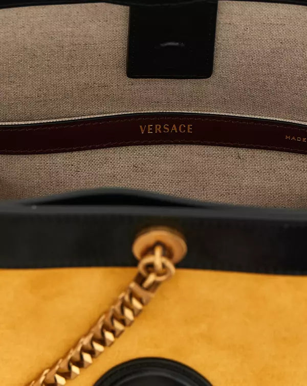 Close-up of a Versace handbag with gold chain detail.