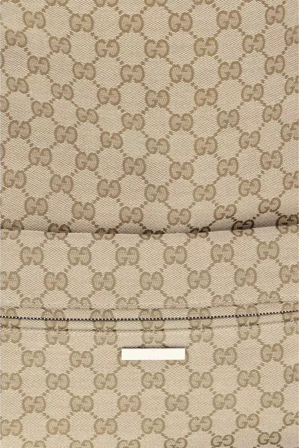 Close-up of a beige and brown monogram fabric with a repeating interlocking GG pattern and a small white rectangular label near the bottom.