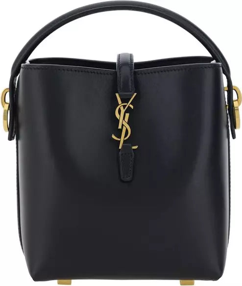 A black leather Saint Laurent bucket bag with gold-tone hardware, featuring the iconic YSL logo clasp on the front flap and a top handle, set against a plain white background.