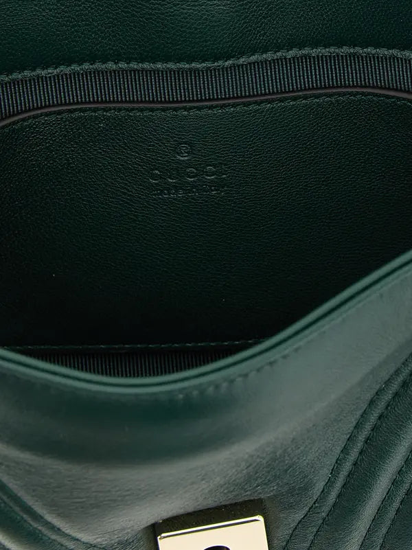Close-up of a green leather bag with a visible brand logo.
