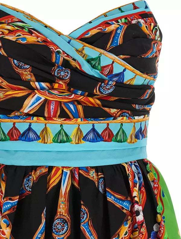 Close-up of a strapless dress with a dramatic gathered bodice and full skirt, featuring a bold multicolor print on a black base with turquoise, gold, red, blue, green, and orange details.