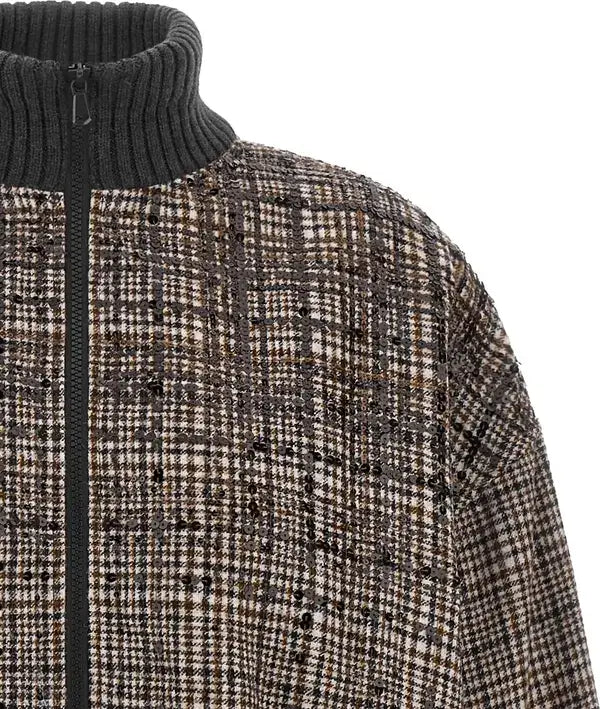 Close-up of a textured tweed zip-up jacket with a dark ribbed turtleneck collar and black front zipper, featuring a brown, beige, and black check pattern.