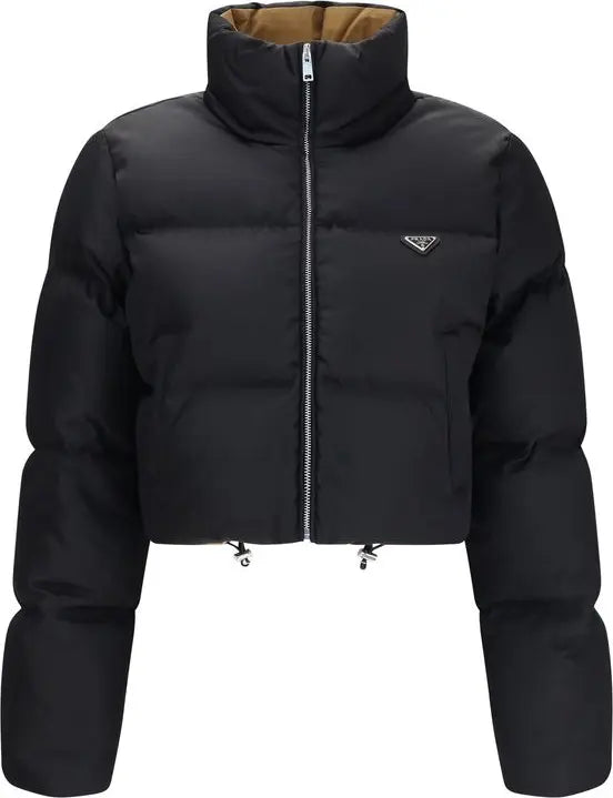 A black cropped puffer jacket with a high stand-up collar, front zipper, and a small silver triangular logo on the left chest, shown on a plain white background.