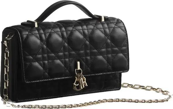 A black quilted leather handbag with a top handle, a silver-tone chain strap, and a gold-tone Christian Dior CD charm on the front flap, set against a plain white background.
