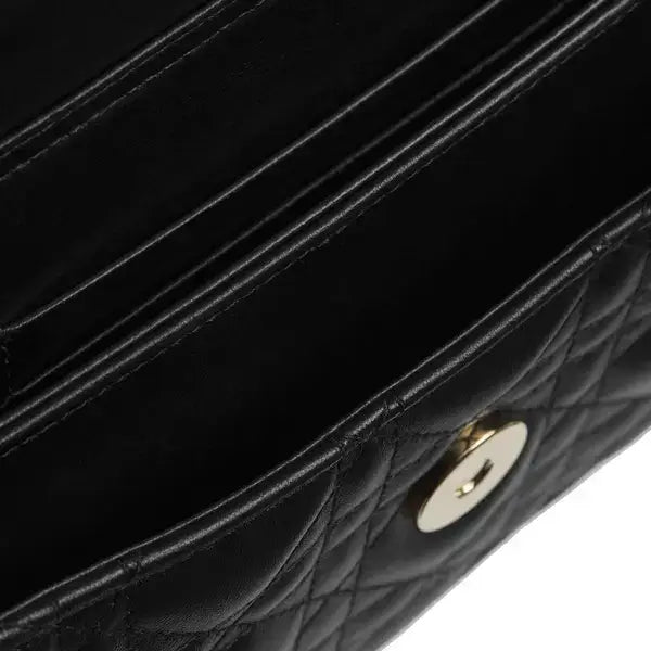 Close-up of a black quilted leather handbag showing the interior card slots, stitching, and a gold-tone snap button.