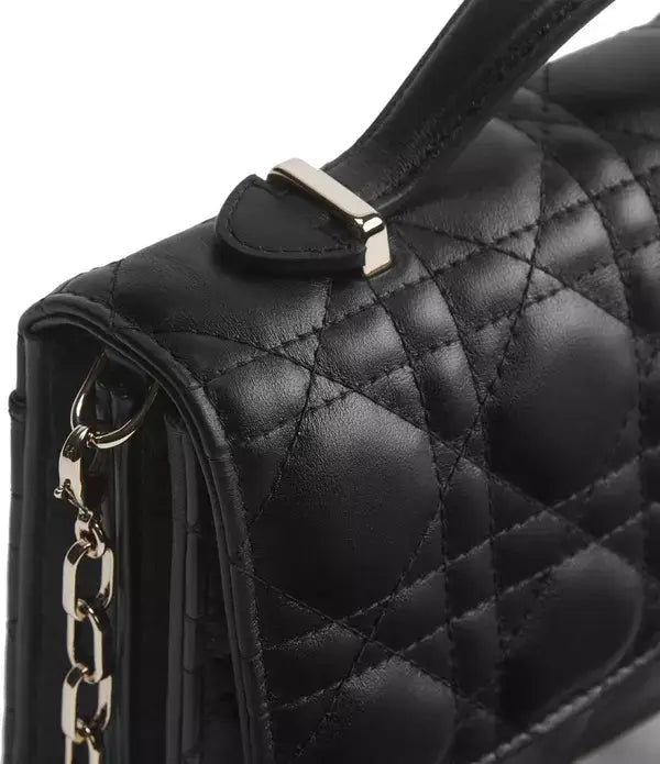 Close-up of a black quilted leather handbag with a top handle, silver-tone hardware, and a chain strap on a white background.