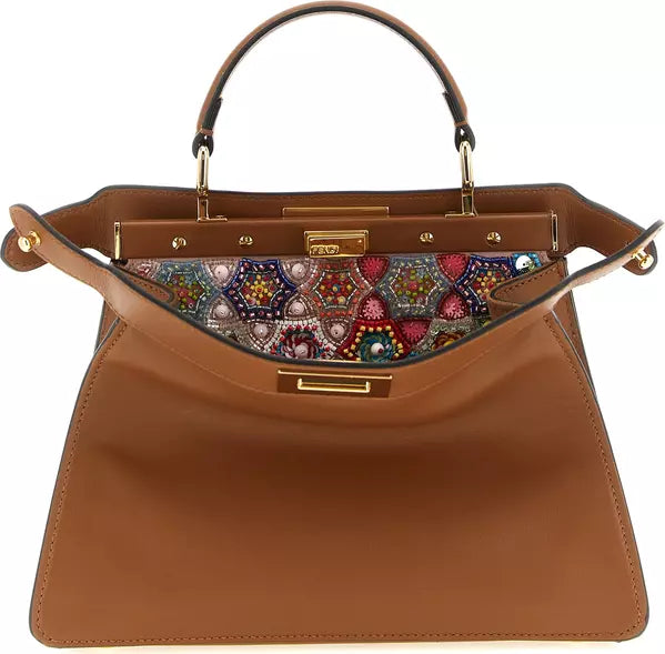 A brown leather handbag with a structured top handle, gold-tone hardware, and a colorful embroidered pattern lining the inner flap.