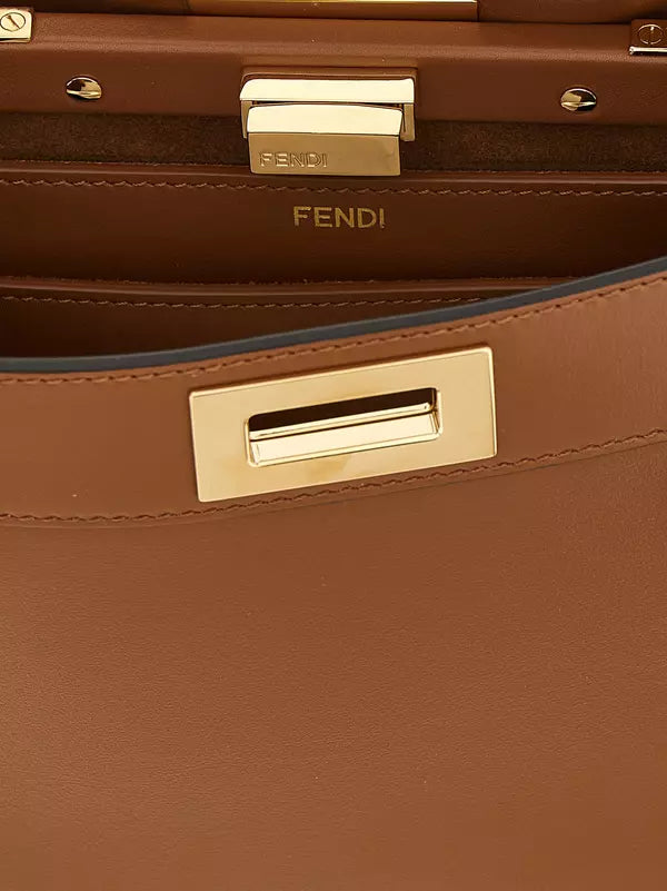 Close-up of a Fendi brown leather handbag showing the interior lining with the Fendi logo, a gold-tone metal clasp, and the edge of a blue lining.