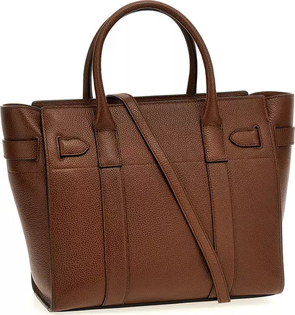 A brown pebbled leather handbag with double top handles and a shoulder strap, shown against a plain white background.