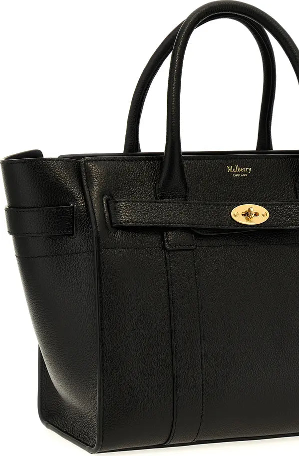 A black pebbled leather Mulberry tote bag with double top handles, a front strap detail, and a gold-tone turn-lock clasp on a white background.