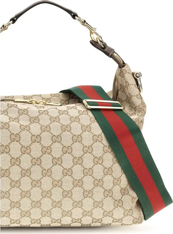Gucci GG Supreme canvas shoulder bag with a green and red web stripe, gold-tone hardware, and a brown leather handle on a white background.