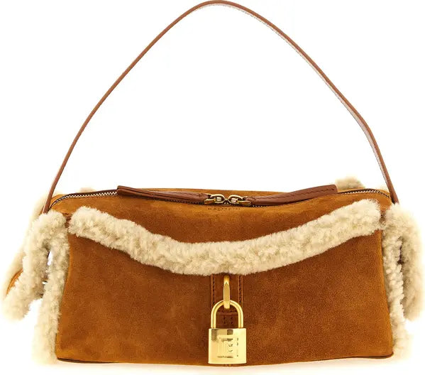 A brown suede shoulder bag with a cream-colored shearling lining, a brown leather shoulder strap, and a gold padlock closure on the front.