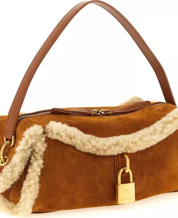 A brown suede shoulder bag with a cream shearling lining, featuring a gold padlock detail and a brown leather handle on a white background.