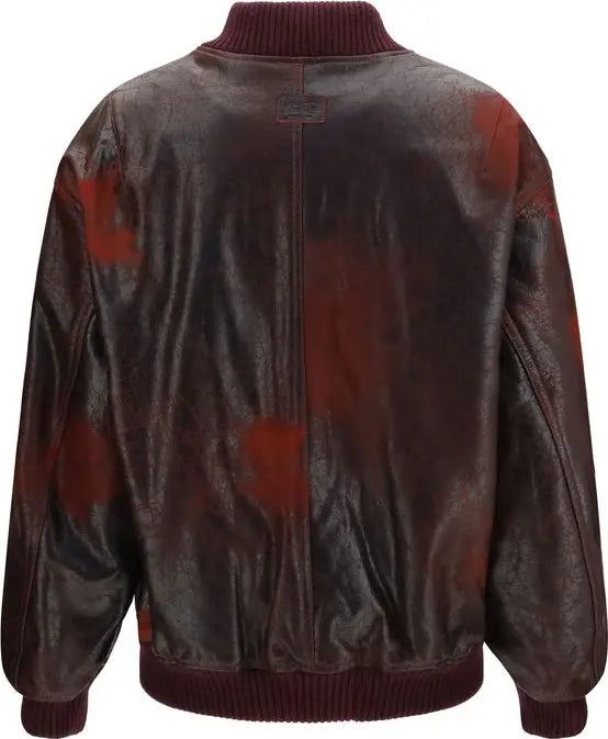 A dark brown leather bomber jacket with a distressed finish and red paint-splatter pattern, featuring a ribbed collar, cuffs, and hem.