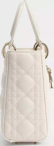 A small quilted handbag in off-white with a diamond-quilted pattern, featuring a top handle, gold-tone metal rings, and a side zipper pull.
