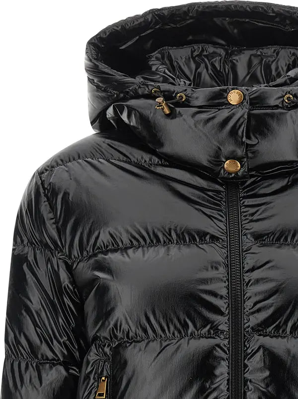 Close-up of a black puffer jacket with horizontal quilting, a high hood with drawstrings, and gold-tone snap and zipper details on a white background.