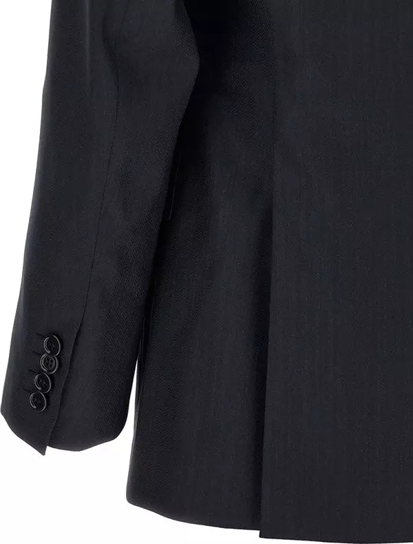Close-up of a black tailored jacket or blazer showing part of the sleeve with four buttons and the body fabric against a white background.