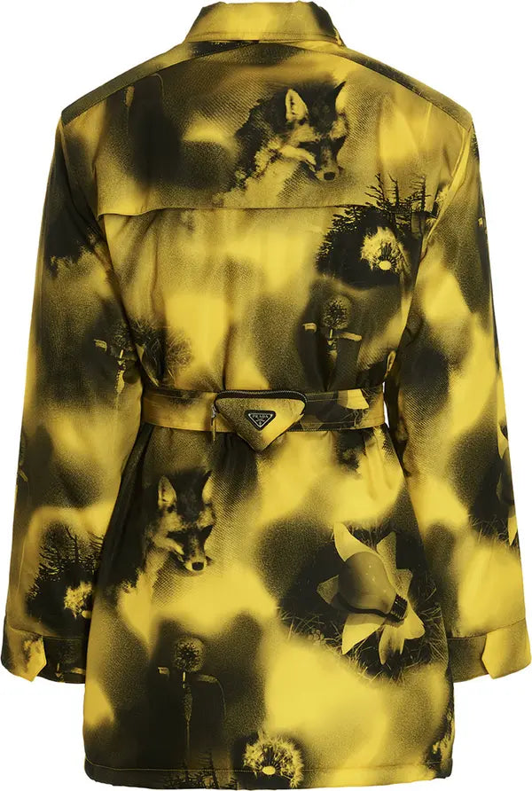 A yellow and black patterned long-sleeve shirt jacket with a matching waist belt and a triangular Prada logo plaque on the belt buckle, featuring an abstract print with fox and flower motifs.
