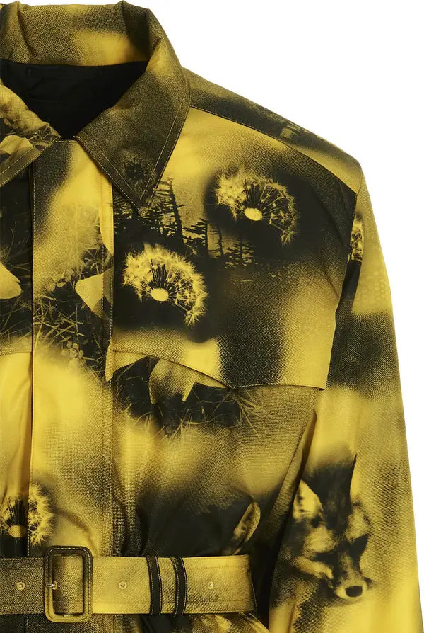 A close-up of a long-sleeve collared shirt jacket featuring a yellow and black abstract print with dandelion and fox motifs, including a matching belt with a gold-tone buckle.