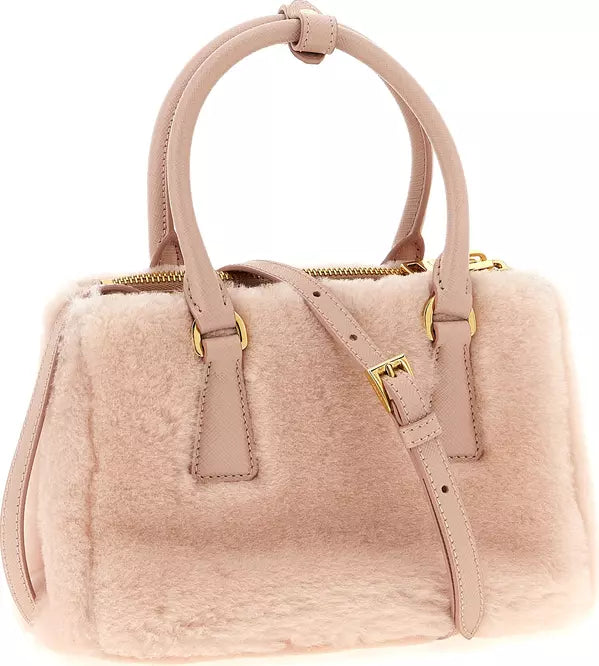 A blush pink handbag featuring a soft, fuzzy faux-fur body with smooth leather handles and a matching shoulder strap, accented by gold-tone hardware.