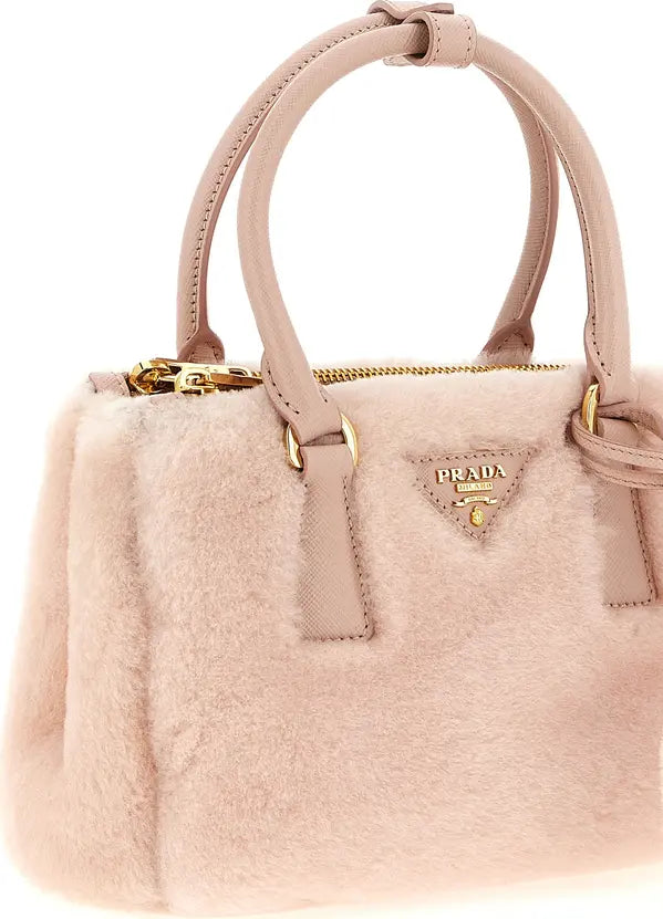A Prada handbag in pale blush pink faux fur with matching leather handles and gold-tone hardware, shown on a clean white background.