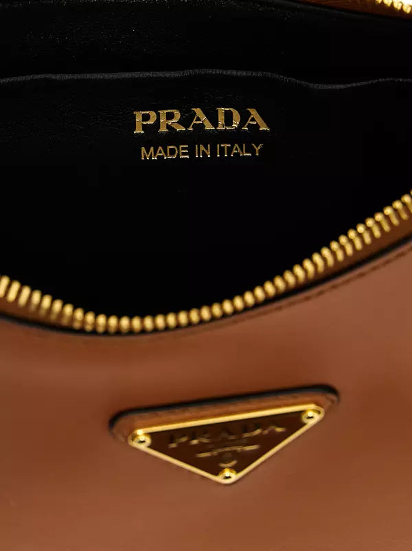 Close-up of a Prada brown leather bag interior showing the black lining with gold &